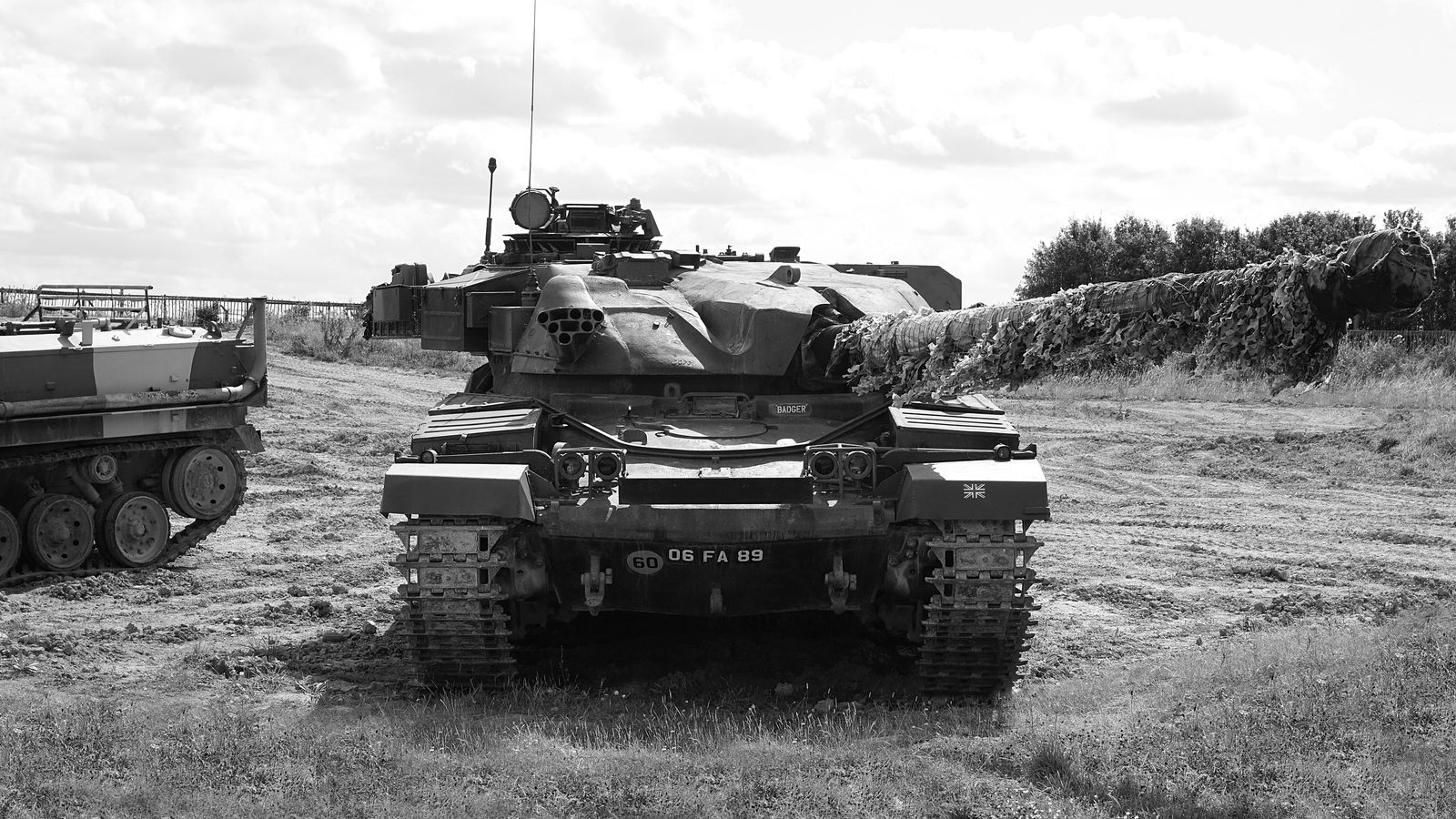 Des chars de combat modernes alignés sur un terrain d'essai, vus de trois quarts, sous un ciel couvert